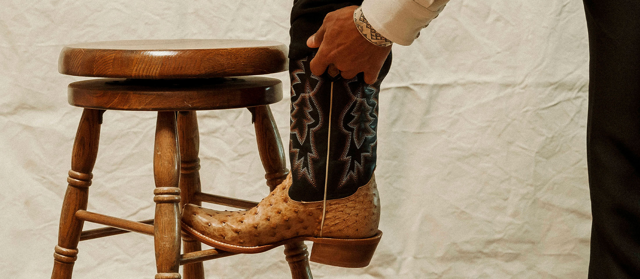 A man resting his foot on a stool and wearing Tony Lama Boots